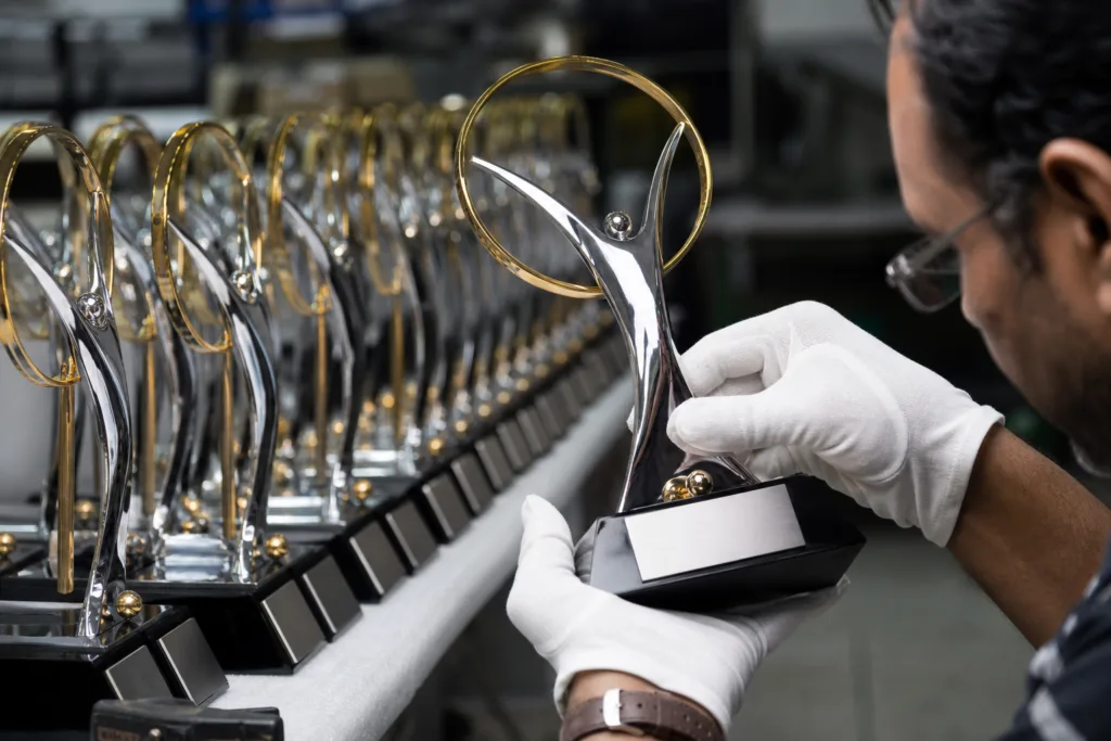 Close-up of plated and painted custom trophies being checked for finish defects and logo quality