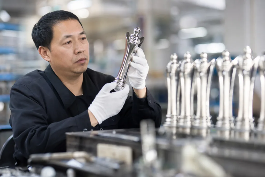 Trophy Mold Cost: What Buyers Should Clarify Before Tooling Approval 2 Technician inspecting a die-cast trophy mold in a manufacturing setting