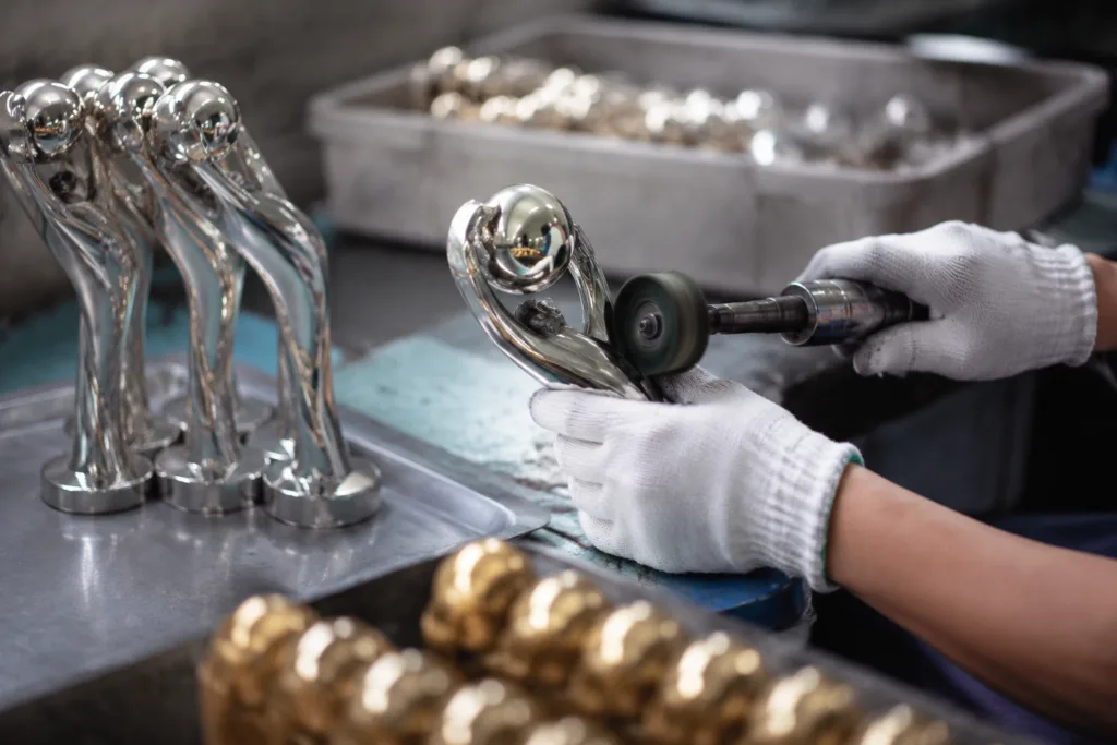 Zinc alloy trophy components being polished and checked before plating in a manufacturing workshop