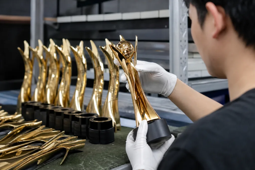 Technician inspecting die-cast trophy parts and assembly alignment in a workshop