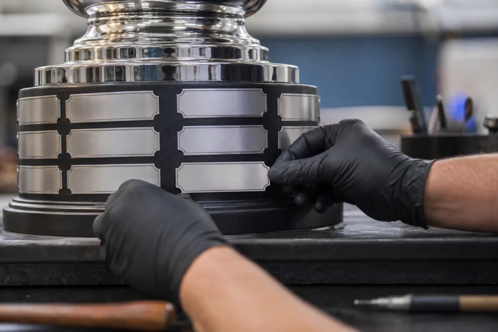Close-up of annual winner nameplates being installed on a custom championship trophy base