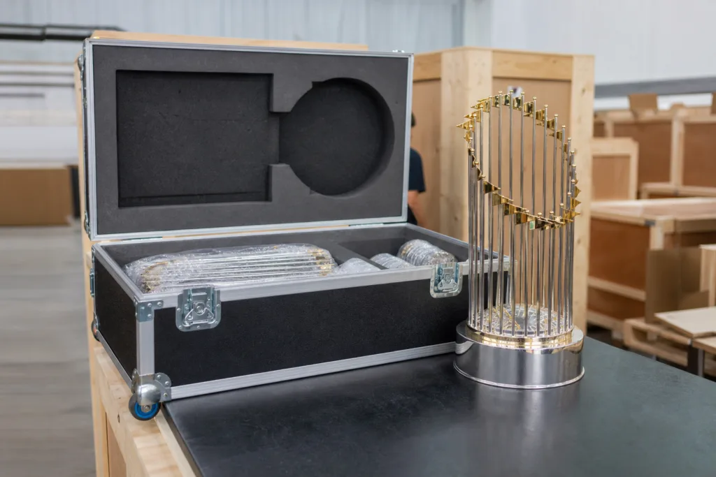 Protective traveling trophy case with fitted interior beside a reusable championship trophy